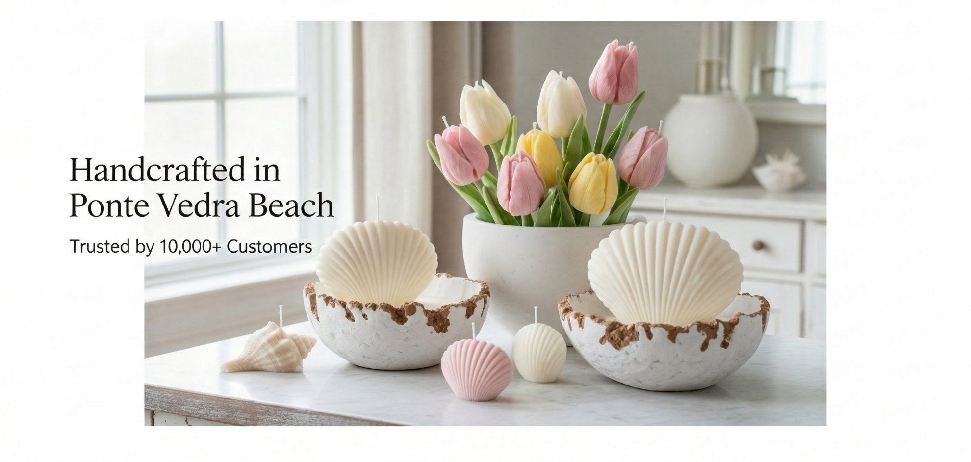Decorative setting with shell-shaped candles and a bouquet of tulips on a table.