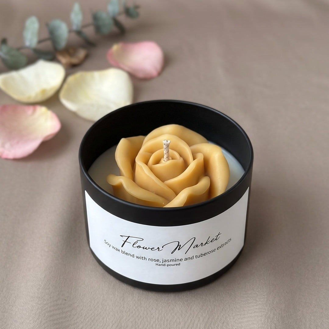 A candle in a matte black round tin with a white label reading &