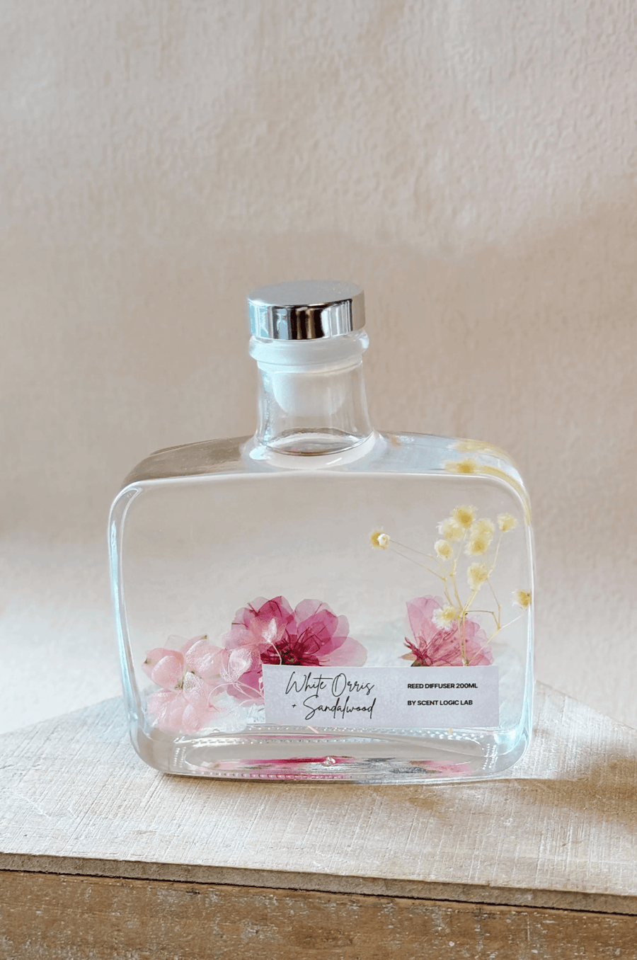 A 6.8 oz glass reed diffuser filled with dried botanicals and fragrance oil, featuring a gold cap and natural reeds.