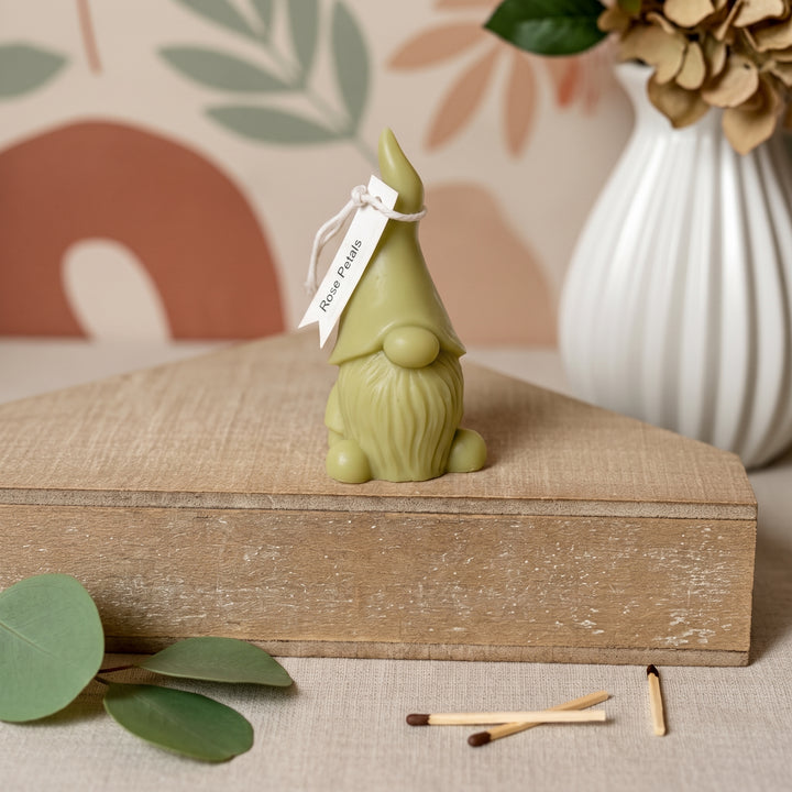 A small olive green gnome figurine with a white paper tag reading &