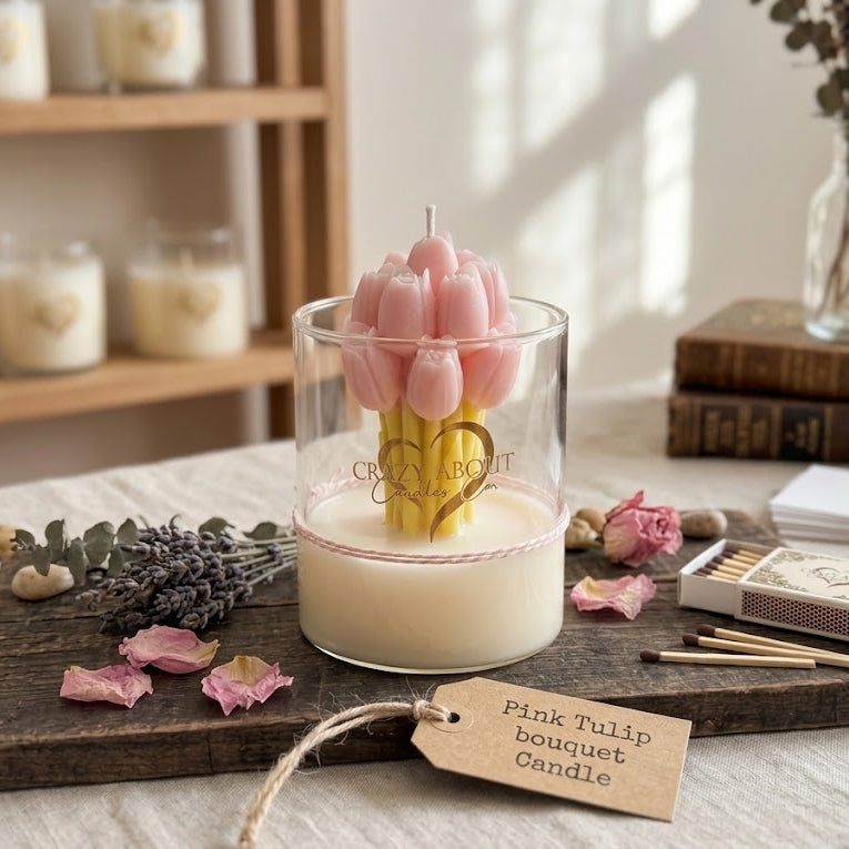 A glass jar candle with a pink tulip bouquet wax top sits on a wooden tray with a paper tag reading &