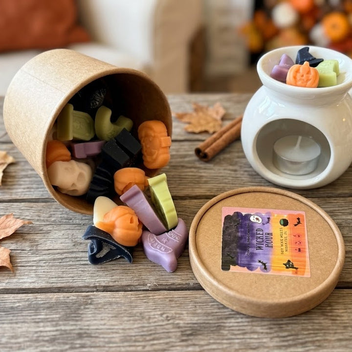 Colorful Halloween wax melts spilling from the Wicked Hour container beside a white melter