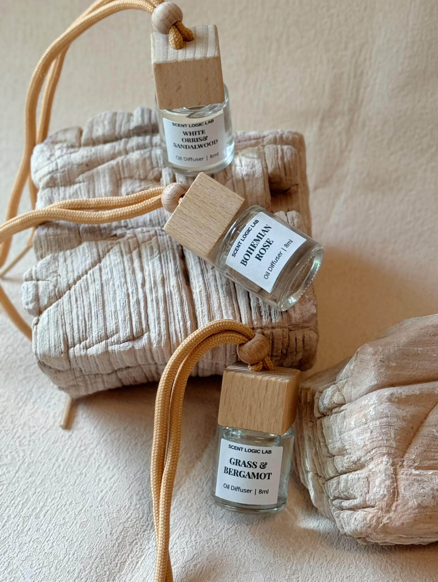 Three artisan car diffusers with natural wood caps and scented oils, displayed on textured surface.