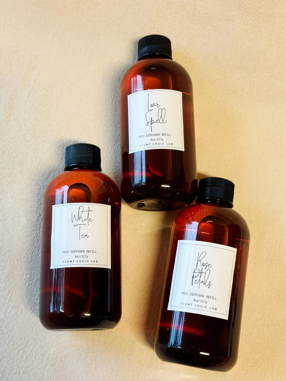 Three 8oz reed diffuser refills in amber bottles: White Tea, Love Spell, and Rose Petal scents.